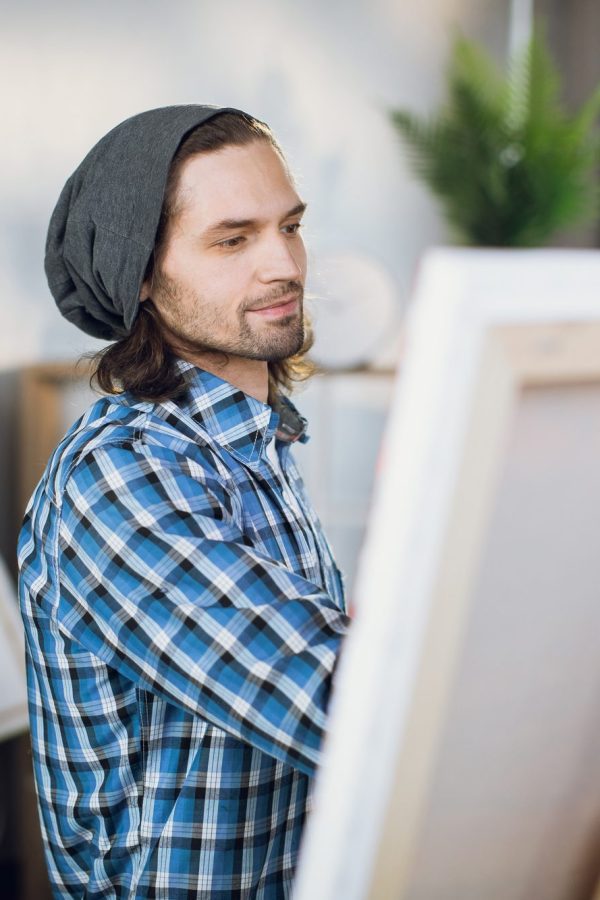 Man drawing with brush on canvas at art studio