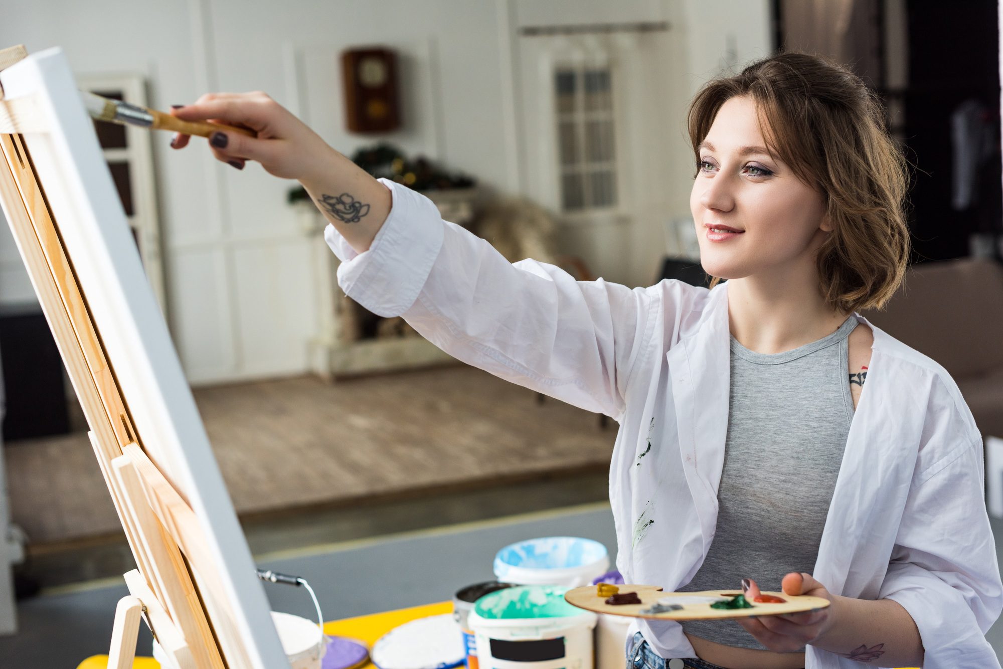Young inspired girl working by easel in light studio